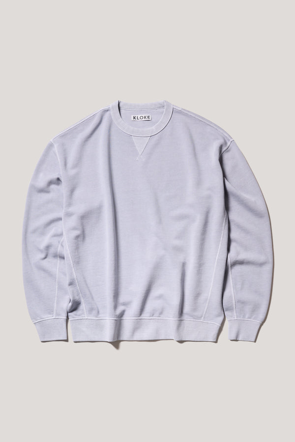 Oversized unisex French terry sweater in pigment-dyed finish, shown on model with relaxed dropped shoulders and flatlock seam detailing.
