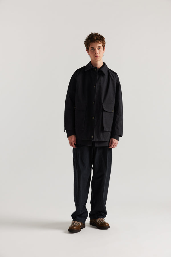 Front view of model in the Jet Black Spectra Jacket ft. short length, buttoned stand collar and 3d Patch Pockets.