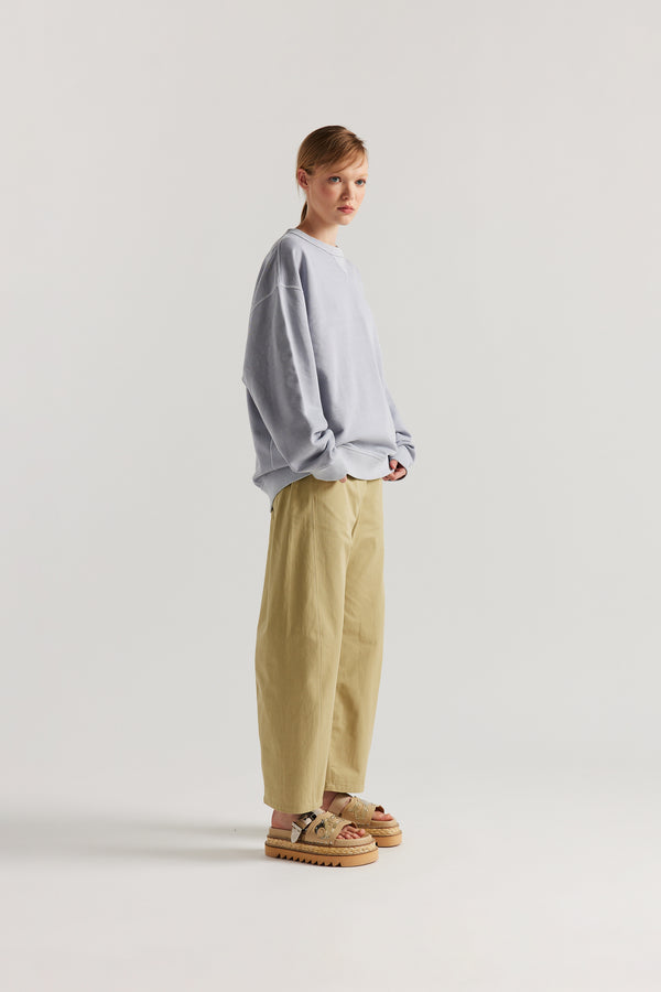 Oversized unisex French terry sweater in pigment-dyed finish, shown on model with relaxed dropped shoulders and flatlock seam detailing.