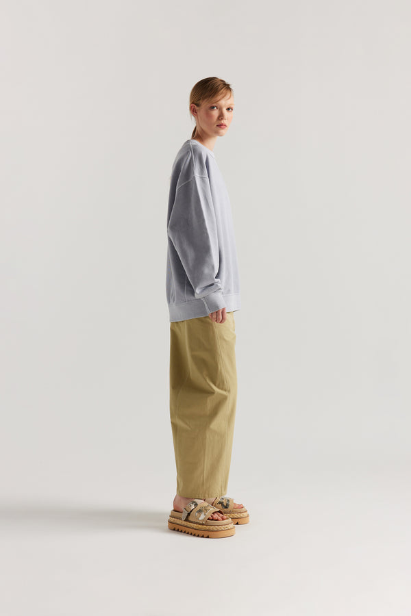 Oversized unisex French terry sweater in pigment-dyed finish, shown on model with relaxed dropped shoulders and flatlock seam detailing.
