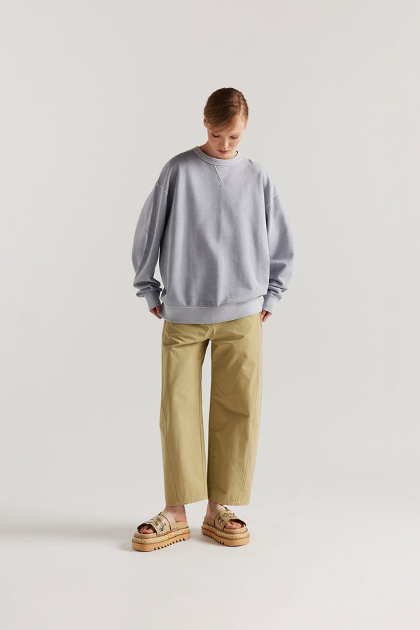 Oversized unisex French terry sweater in pigment-dyed finish, shown on model with relaxed dropped shoulders and flatlock seam detailing.

