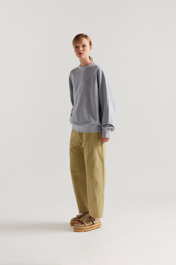 Oversized unisex French terry sweater in pigment-dyed finish, shown on model with relaxed dropped shoulders and flatlock seam detailing.
