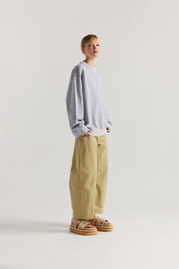 Oversized unisex French terry sweater in pigment-dyed finish, shown on model with relaxed dropped shoulders and flatlock seam detailing.