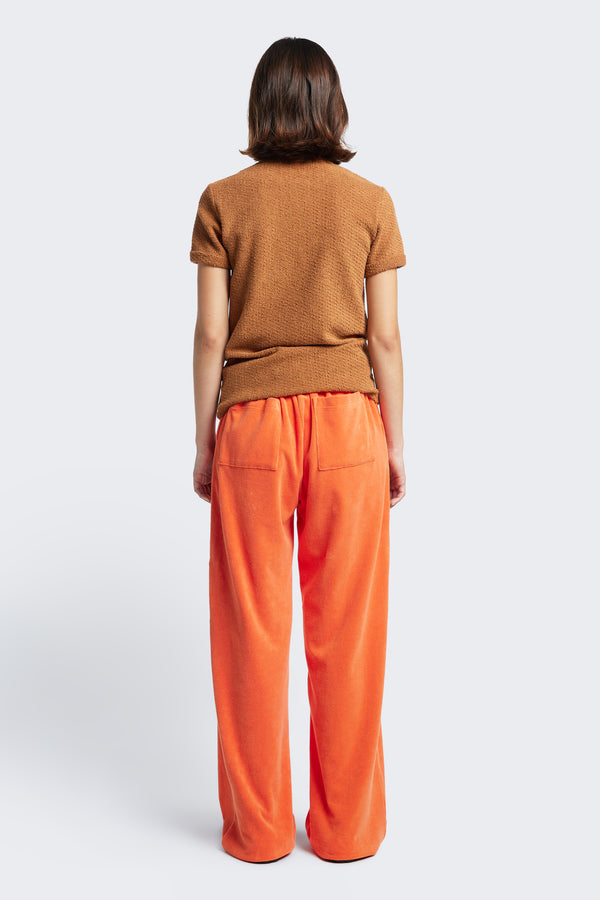 The Back of the Prone Towelling Track Pant, a slouchy track pant with two back pockets and made from Okeo-tex standard cotton terry in Tangerine Orange.