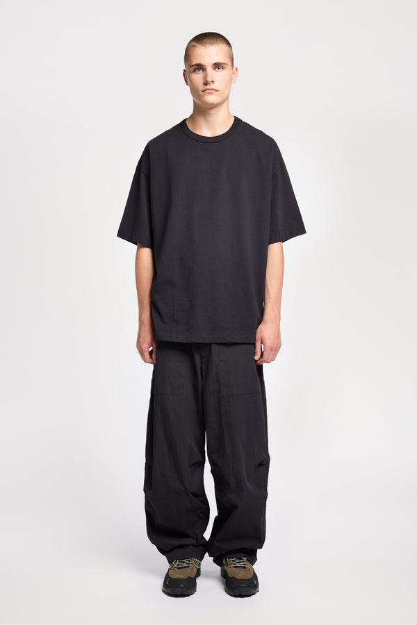 Men - front of model in Monolith Unisex Tee in Black.  Oversized relaxed fit. Available in 6 sizes. Made form 100% Organic Cotton. 