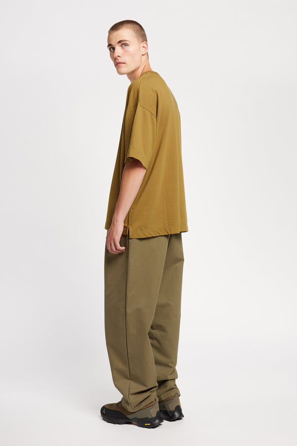 Back of male model in Monolith Unisex Tee in Olive Oil.  Oversized relaxed fit. Available in 6 sizes.