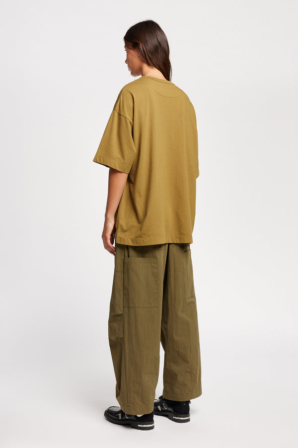 Back of female model in the Monolith Unisex Tee in Olive Oil. Oversized relaxed fit. Available in 6 sizes. Made from 100% Organic Cotton. 