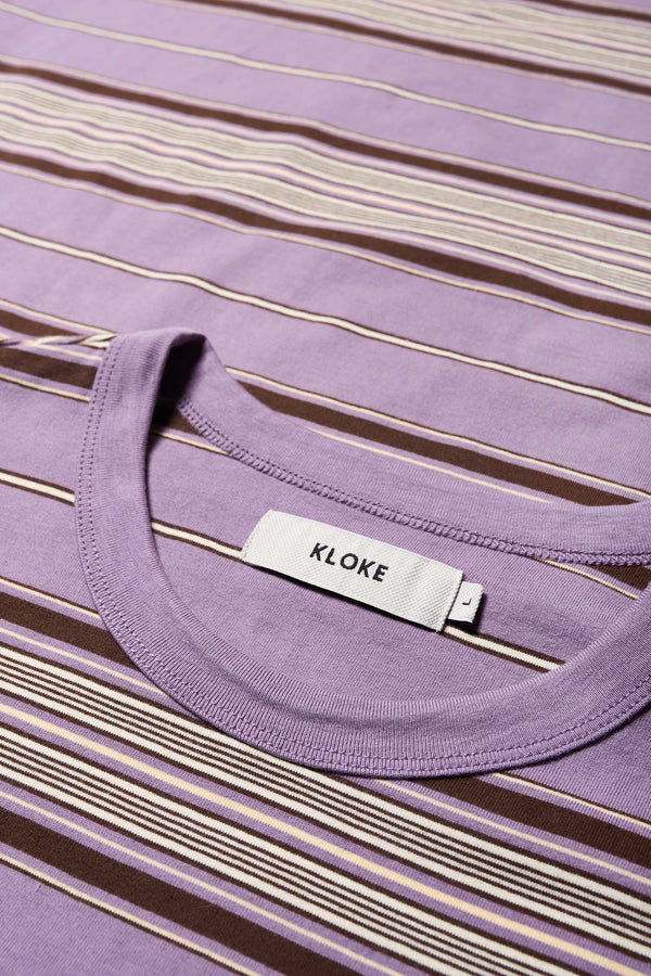 Close up details of The Attain T-Shirt in purple, a classic fit t-shirt in ticking stripe cotton jersey, featuring a rib-bound cover-stitched neckline and reinforced back. Available in 5 sizes. 