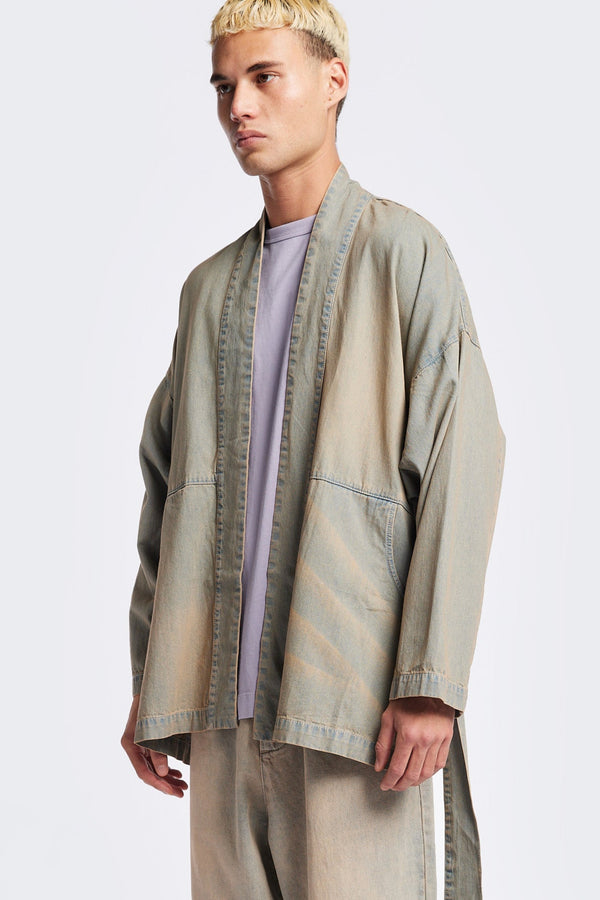Front of the unisex ( men) Subterra Wide wrap shawl collar jacket with kimono-style sleeves, crafted from cotton denim, featuring front patch pockets and a waist tie to cinch the loose silhouette. Available in 5 sizes.  