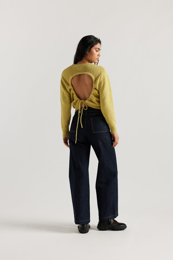 Back of female model in the straight wide-leg denim jeans indigo with a higher-rise waist, patch pockets, and back yoke detail, shown from the front.
