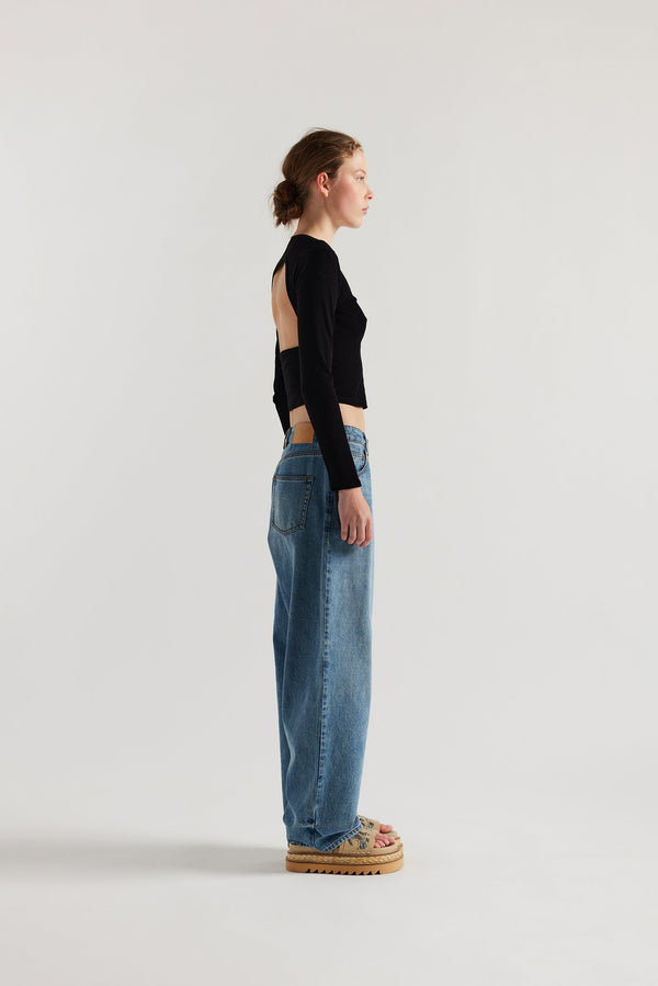 Side view of Model wearing Kloke straight-leg jeans in mid-blue Japanese denim, featuring a mid-rise waist and relaxed silhouett