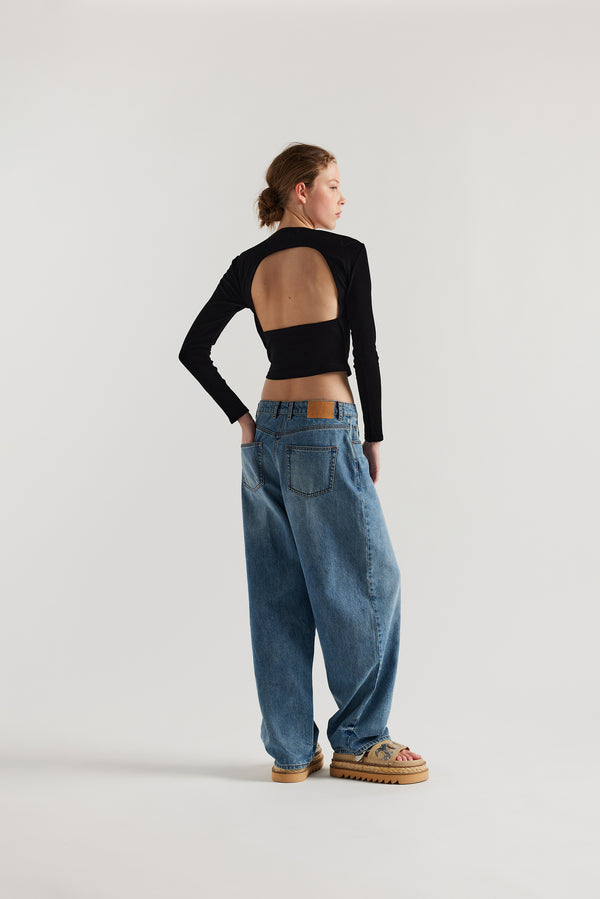 Back view of Model wearing Kloke straight-leg jeans in mid-blue Japanese denim, featuring a mid-rise waist and relaxed silhouett