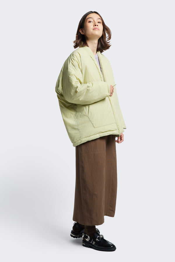 Side profile of the Abeyance Quilted Wrap Coat Sand, a kimono style puffer jacket styled with the Anima Skirt Brown 