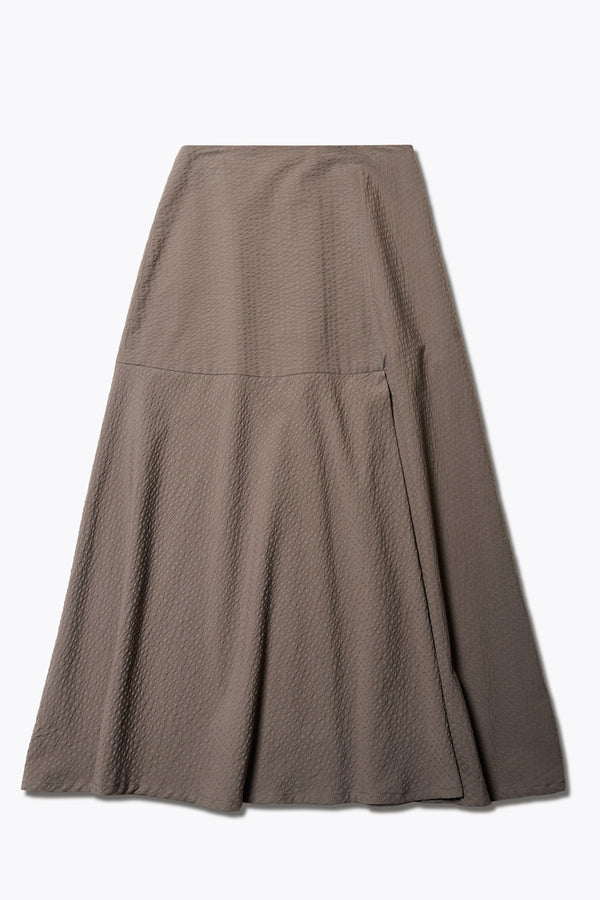 The Abroad Panel Skirt, fitted at the waist with a bias-cut maxi silhouette, made from 100% cotton in Brown Seersucker. Features panel details, side pockets, and an invisible back zip. Available in 6 sizes