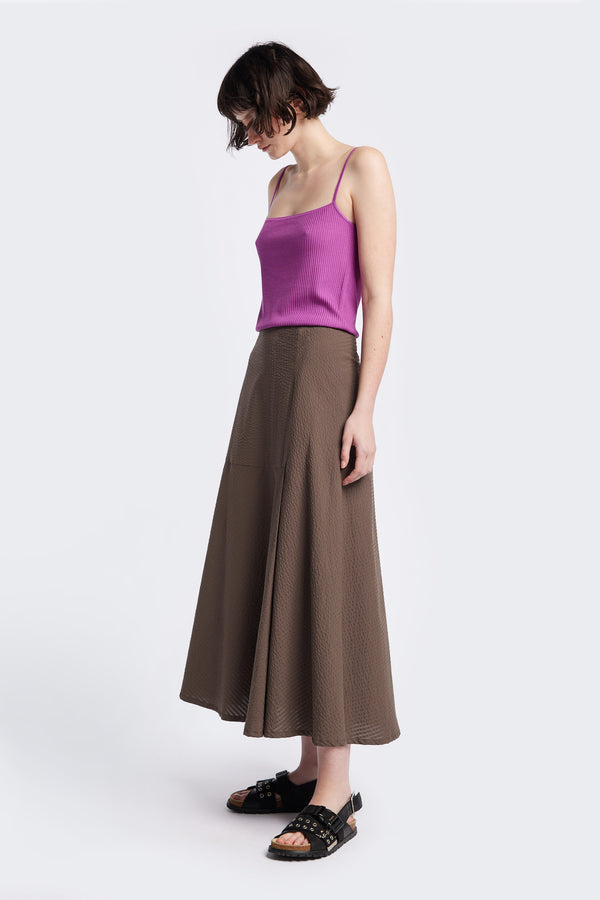 Abroad Panel Skirt, fitted at the waist with a bias-cut maxi silhouette, made from 100% cotton in Brown Seersucker. Features panel details, side pockets, and an invisible back zip. Available in 6 sizes.