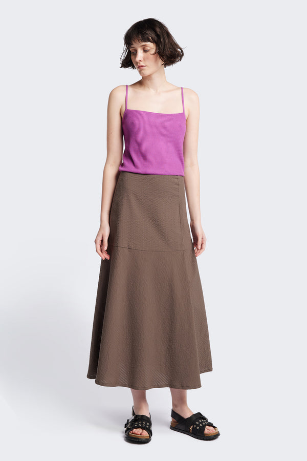 The Abroad Panel Skirt, fitted at the waist with a bias-cut maxi silhouette, made from 100% cotton in Brown Seersucker. Features panel details, side pockets, and an invisible back zip. Available in 6 sizes.