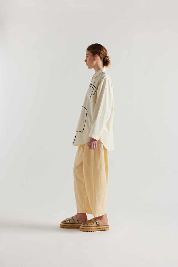 Ecru off white, Ache Embroidered Shirt side view on female model, with embroidered motifs, long sleeves, and built-in collar