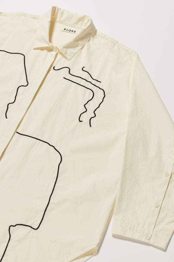 Close up fabric + details shot of the Ecru off white Ache Embroidered Shirt, with embroidered motifs, long sleeves, and built-in collar