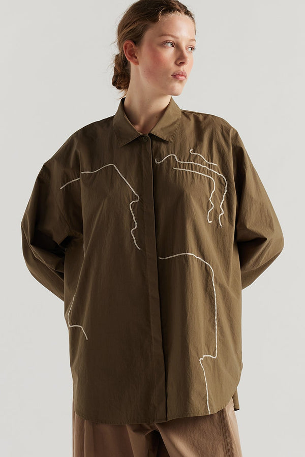 Olive green/brown Ache Embroidered Shirt front view on female model, with embroidered motifs, long sleeves, and built-in collar