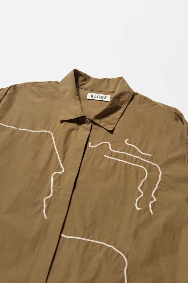 Close up fabric details shot of the Olive green/brown Ache Embroidered Shirt, with embroidered motifs, long sleeves, and built-in collar