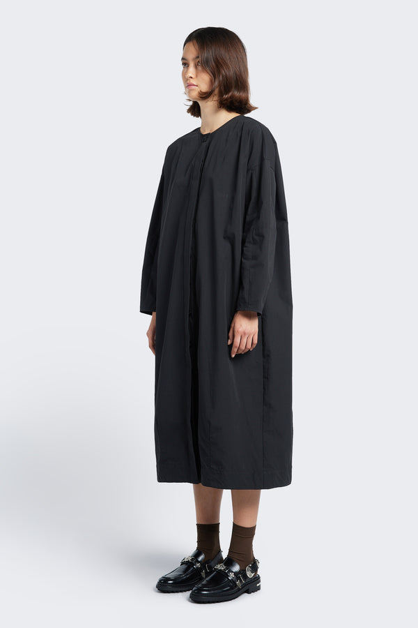 The Agora Dress Black, a slightly boxy oversized style with a round neckline and concealed button-through placket at the front.