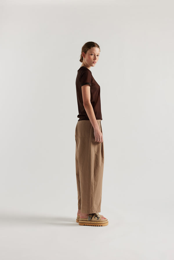 Side of the model in the Fawn brown Amber Pant. A Semi-tailored tapered pant with pleat waistband detail and front seam topstitching.