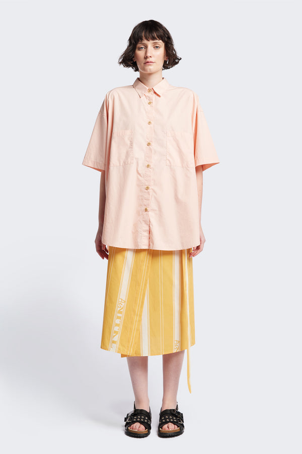 (women) Relaxed loose-fitting boxy short-sleeve shirt with back button placket, scoop hemline, and chest patch pockets, crafted in lightweight cotton poplin. Available in 5 sizes.  