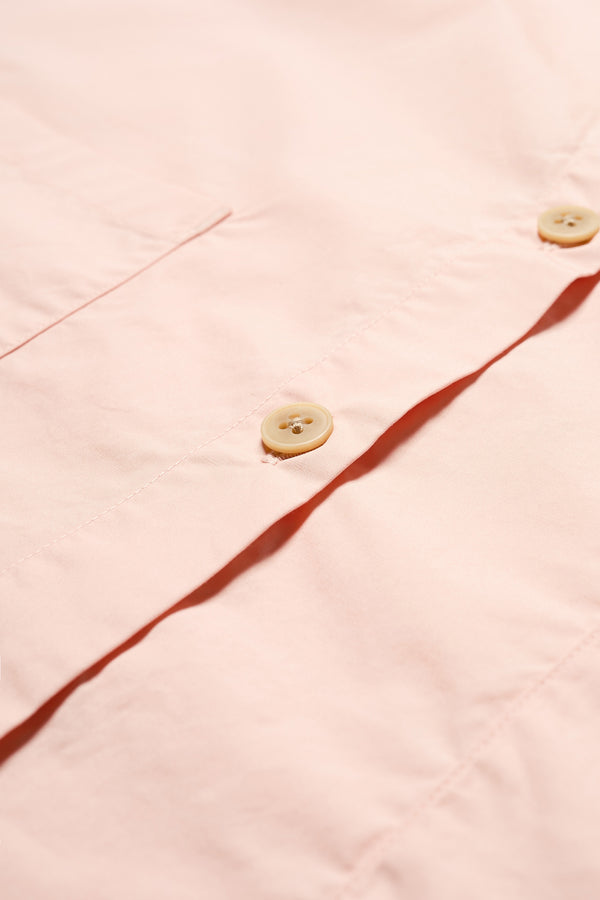 Details of the Aquifer in peach, a relaxed loose-fitting boxy short-sleeve shirt with back button placket, scoop hemline, and chest patch pockets, crafted in lightweight cotton poplin. Available in 5 sizes. 