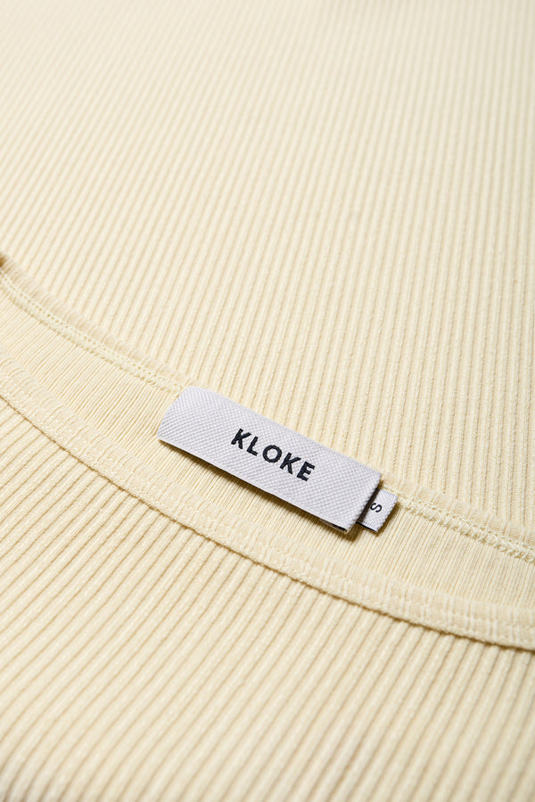 Close up details of the arbour top, a slim-fitting t-shirt-style top, in pale yellow. With a boat neckline and single bind trim, made from fine Japanese rib knit with slight stretch, perfect for casual and stylish outfits