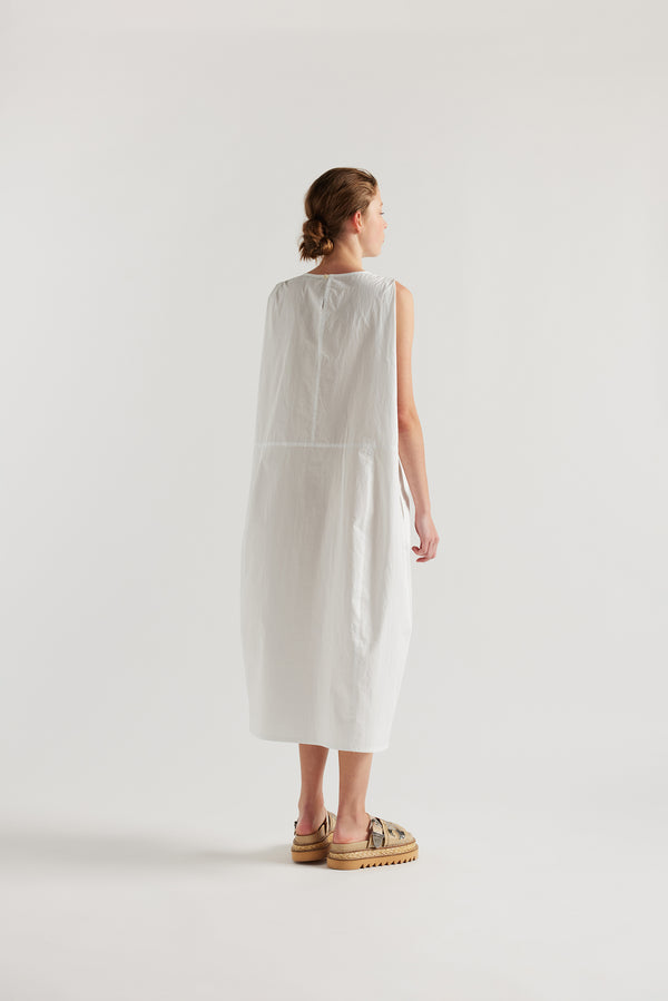 Back view of female model in the white  Aureole Dress front view showing panelled detailing and relaxed skirt with front inseam split
