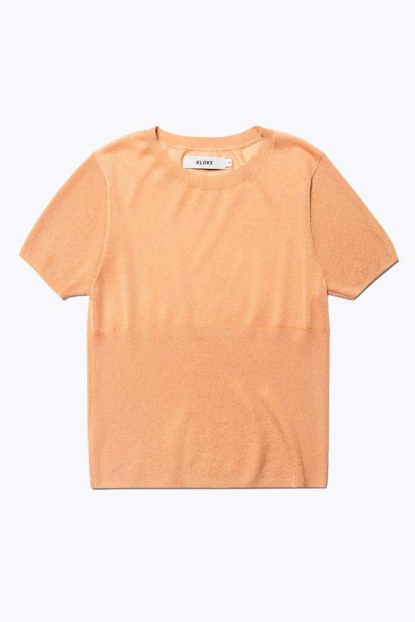 Flat Front of The Break Knit Top in pale orange, crafted from fine-gauge cotton. Features a crew neckline, short sleeves, and a slim fit with a high rib detail below the chest.