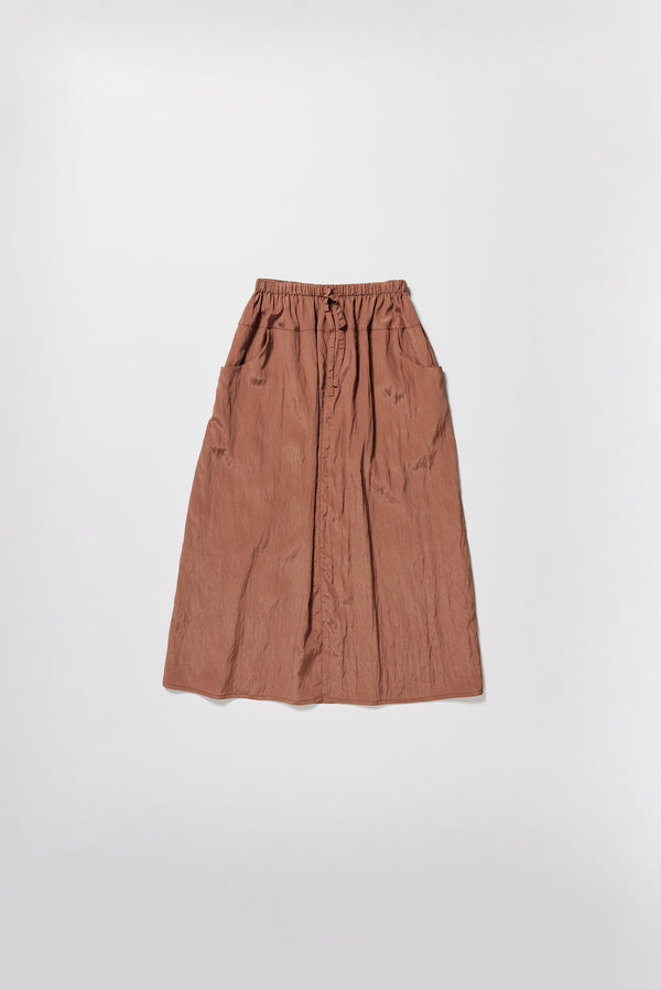 Flat front of the brown Calm Skirt with panelled construction, scoop pockets and elasticated drawcord waistband in lightweight textured fabric.
