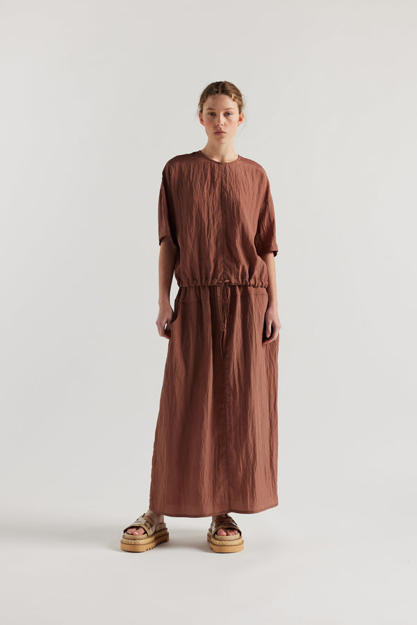 Front of Model in the brown Calm Skirt with panelled construction, scoop pockets and elasticated drawcord waistband in lightweight textured fabric.