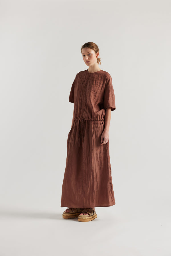 Front of Model in the brown Calm Skirt with panelled construction, scoop pockets and elasticated drawcord waistband in lightweight textured fabric.