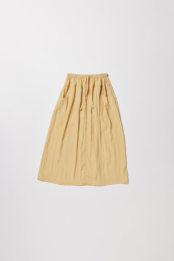 Flat front of the beige Calm Skirt with panelled construction, scoop pockets and elasticated drawcord waistband in lightweight textured fabric.