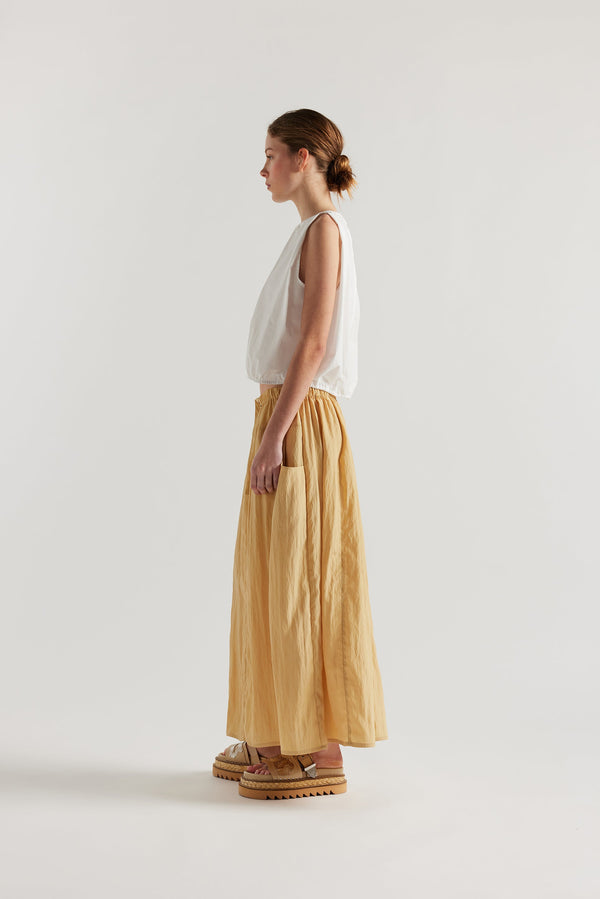 Side of Model in the beige Calm Skirt with panelled construction, scoop pockets and elasticated drawcord waistband in lightweight textured fabric.