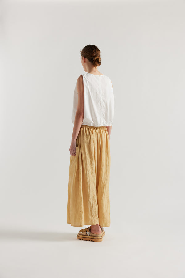Back of Model in the beige Calm Skirt with panelled construction, scoop pockets and elasticated drawcord waistband in lightweight textured fabric.