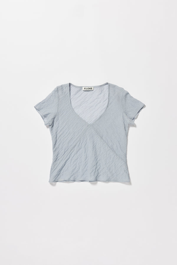 Flat front of the Pale Blue Centered top. A Slim-fit V-neck top in sheer textured fabric with cap sleeves and bias cut silhouette.
