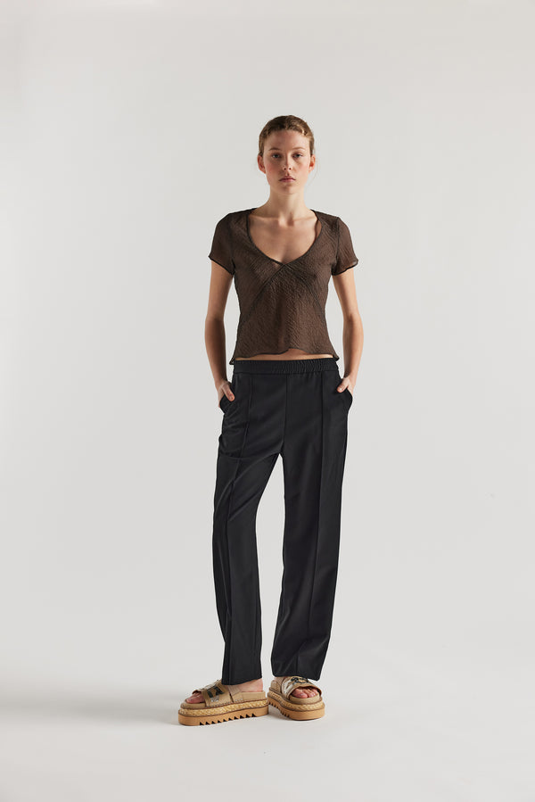 Front view of Model in the brown Centered top. A Slim-fit V-neck top in sheer textured fabric with cap sleeves and bias cut silhouette.