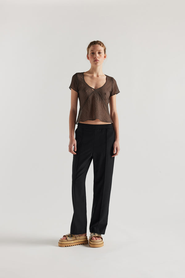 Front view of Model in the brown Centered top. A Slim-fit V-neck top in sheer textured fabric with cap sleeves and bias cut silhouette.