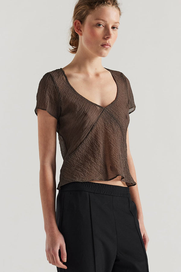 Front view of Model in the brown Centered top. A Slim-fit V-neck top in sheer textured fabric with cap sleeves and bias cut silhouette.