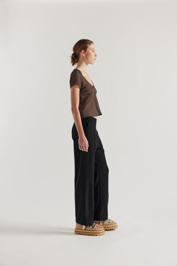 Front side view of Model in the brown Centered top. A Slim-fit V-neck top in sheer textured fabric with cap sleeves and bias cut silhouette.