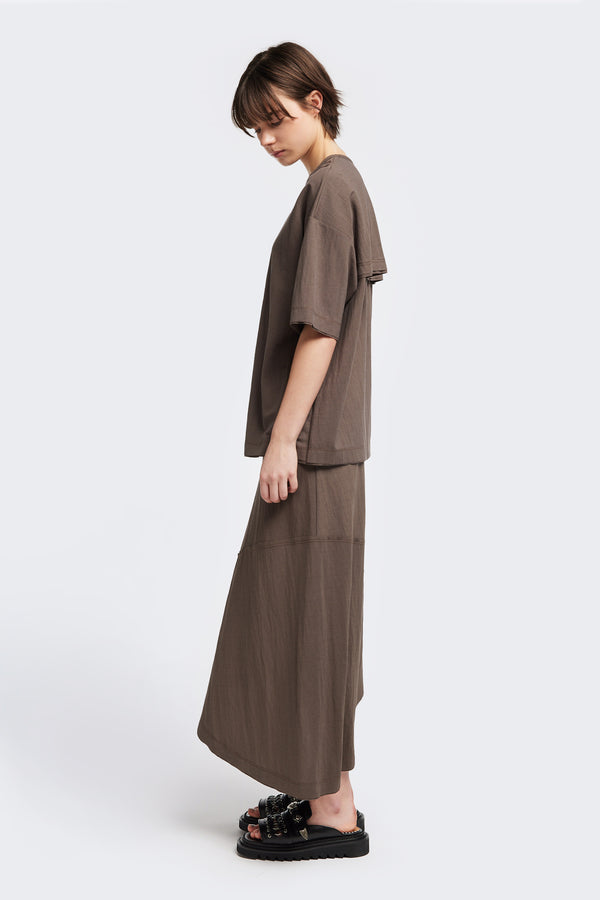 Side of the Chaise top in Taupe, a relaxed crew-neck top in a Japanese rayon blend with short sleeves, boxy fit, raw hemline, and exposed seam detail across the mid-back.