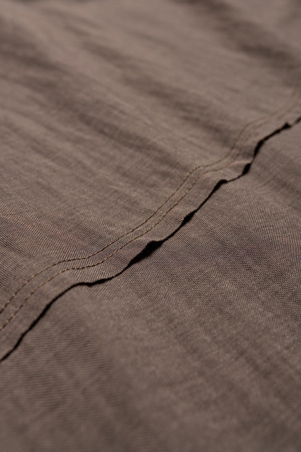 Close up of the Chaise top in Taupe, a relaxed crew-neck top in a Japanese rayon blend with short sleeves, boxy fit, raw hemline, and exposed seam detail across the mid-back.