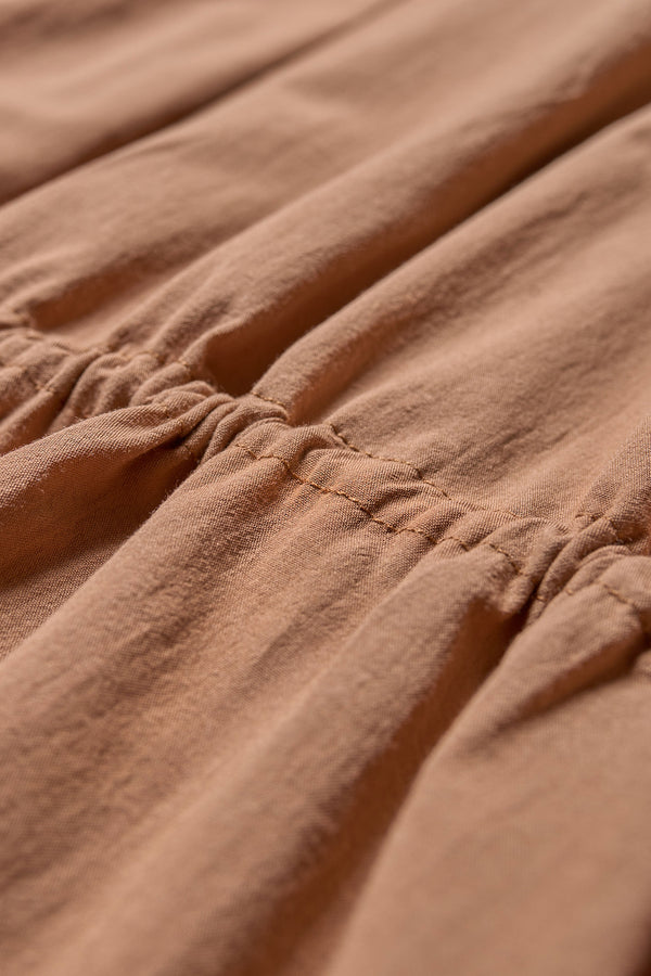 Close up fabric view of the cloud dress in toffee brown, a relaxed-fit sleeveless dress featuring wide shoulder straps and a scoop neckline.