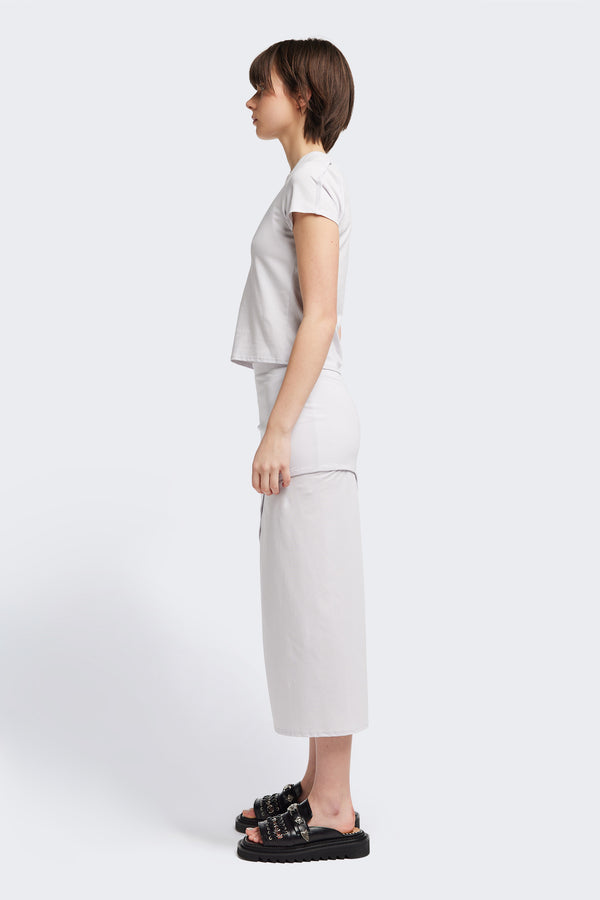 Side view of The Cumulus Skirt in white ice blue. A Slim, mid-calf dress in a cotton blend with stretch, featuring a curved bound seam for a flattering silhouette.