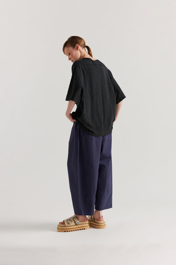 Back view of model in the Jet Black Declare Tee in pigment-dyed slub cotton with relaxed boxy fit - highlighting the flatlock seam detailing 