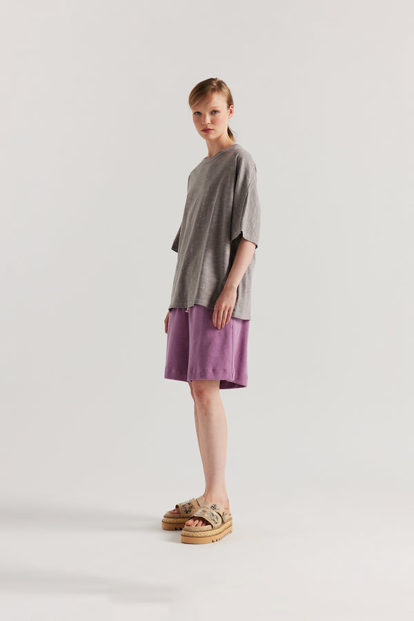 Side view of model in the Mauve Declare Tee in pigment-dyed slub cotton with relaxed boxy fit
