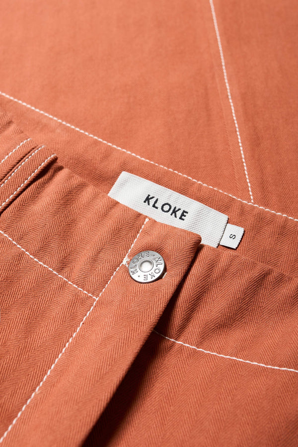 Close up fabric view of the Delta pant in Burnt Orange, a tailored casual pant in premium cotton herringbone twill with contrast stitch panelling. Straight leg and tailored fit for a sleek, flattering polished finish. Available in 6 sizes. 