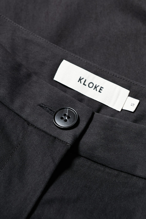 Close up fabric shot of Tailored Depth Short in Black, crafted from soft cotton with pleat front detail, slant pockets, and a relaxed wide leg. Finished with back dart detailing and patch pockets. Available in 6 sizes. 